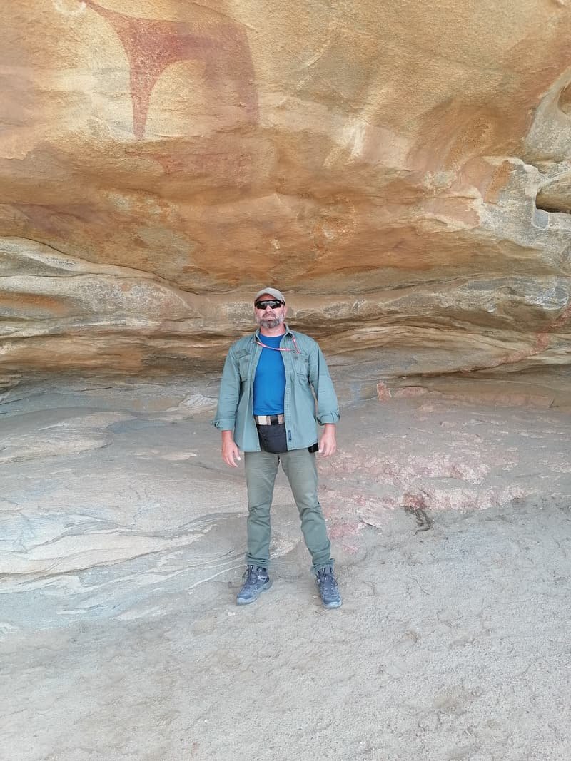 Standing before a wall of layered rock