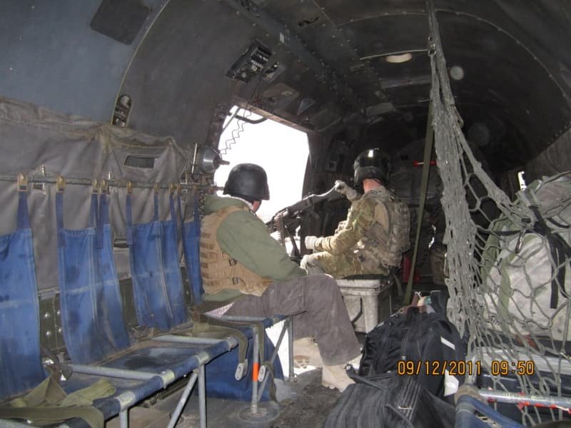 Inside a transport helicopter, a door gunner at his position